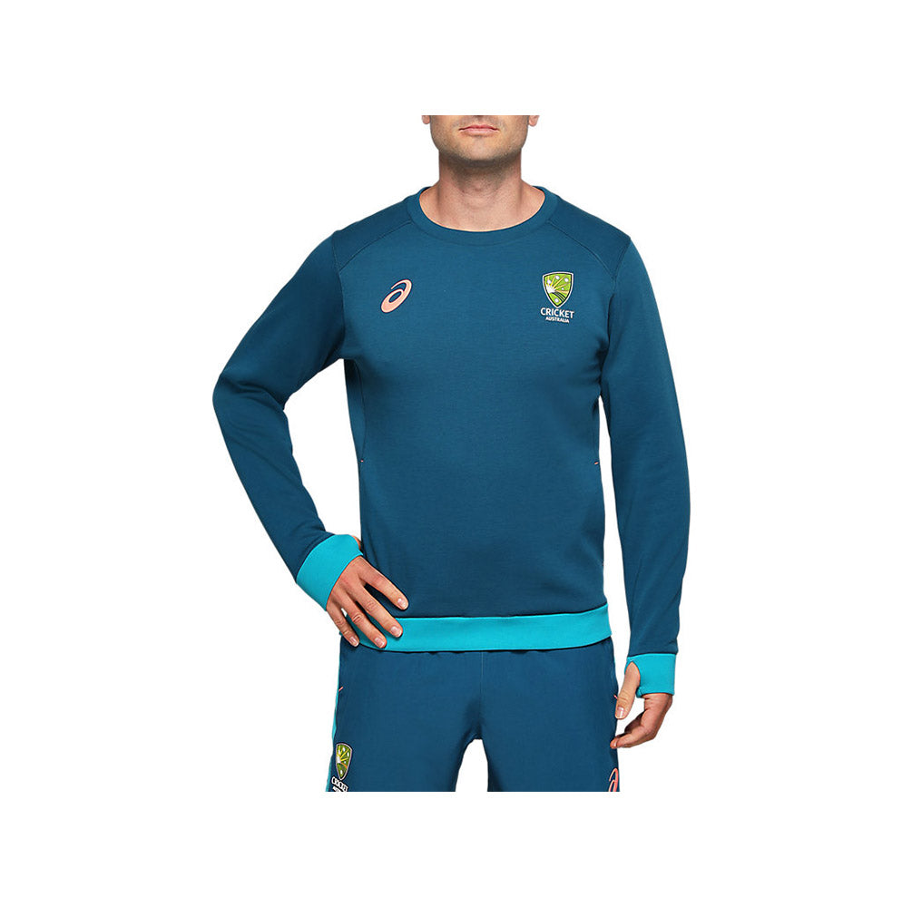 A male model wearing a long-sleeved Cricket Australia crew fleece with teal with the Asics and Cricket Australia logos.