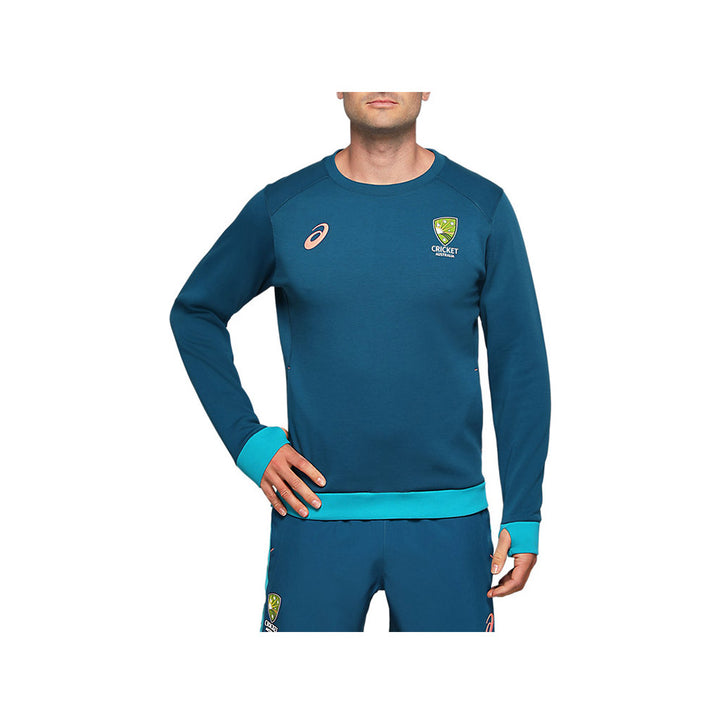 A male model wearing a long-sleeved Cricket Australia crew fleece with teal with the Asics and Cricket Australia logos.