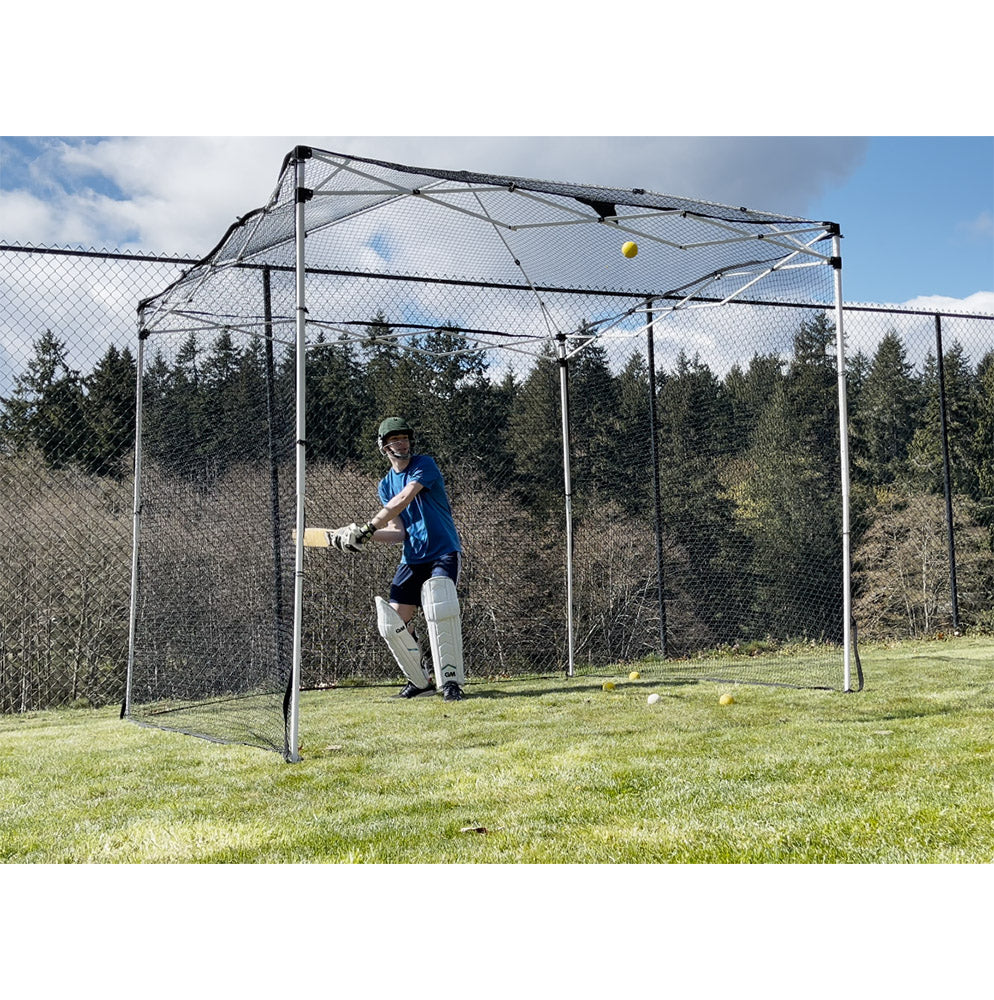 A person practicing cricket in a backyard with a cricket net set up.