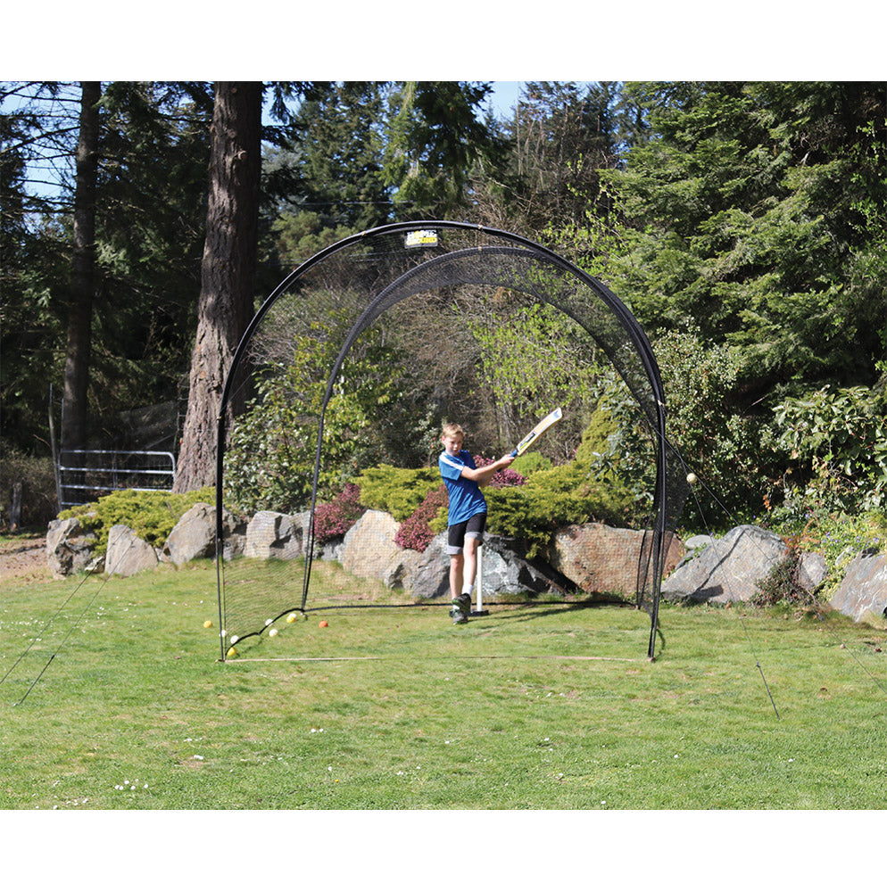 A person is practicing cricket batting against a cricket net which is set up outdoors.