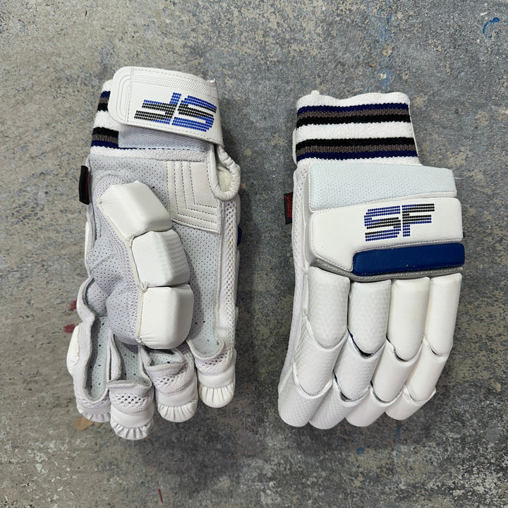 Pair of white cricket gloves with SF brand logos on a gray surface