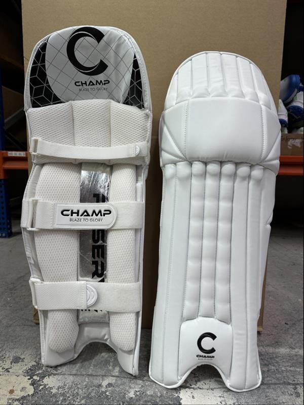 Pair of white cricket pads with 'Champ' branding on a concrete floor.