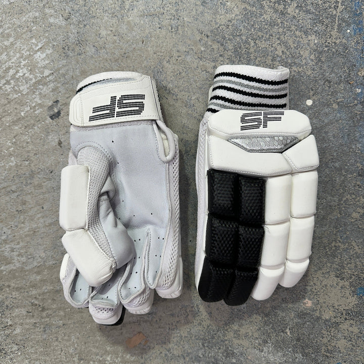 Pair of white and black gloves with 'SF' branding on a gray surface