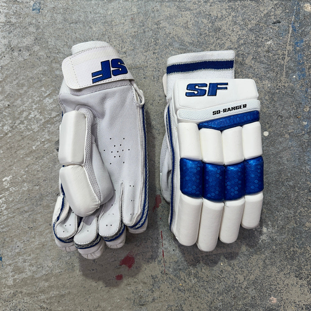 Pair of white and blue cricket gloves with SF branding on a gray surface.