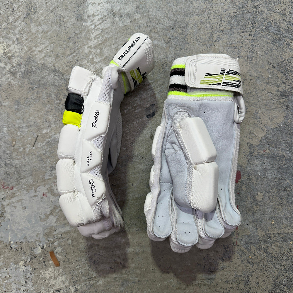 Pair of white cricket gloves with green accents on a gray surface