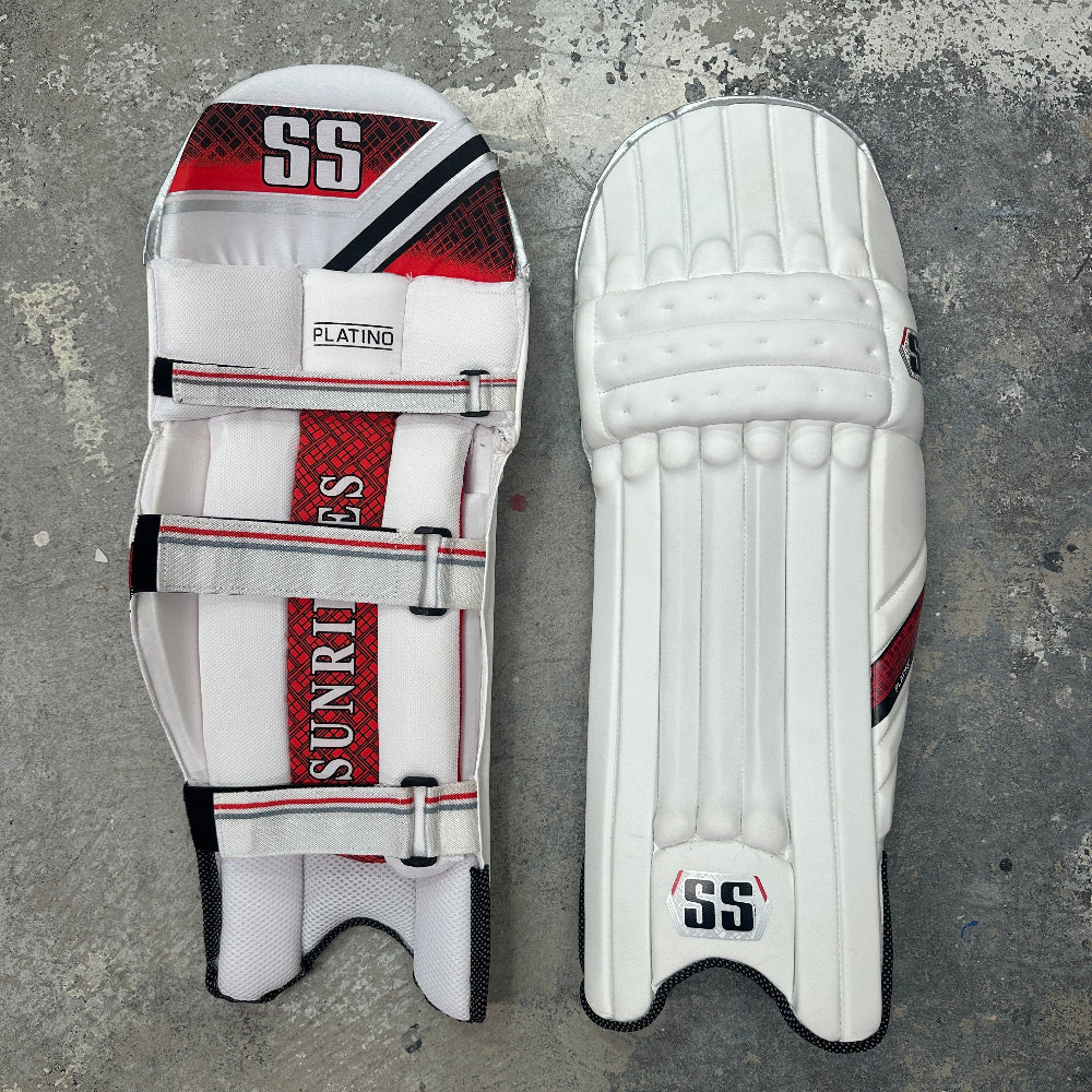 Pair of white cricket pads with red and black accents and SS branding on a gray background