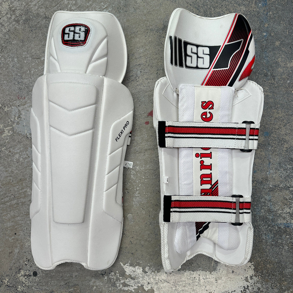 Pair of white SS cricket pads with red and black accents on a gray background