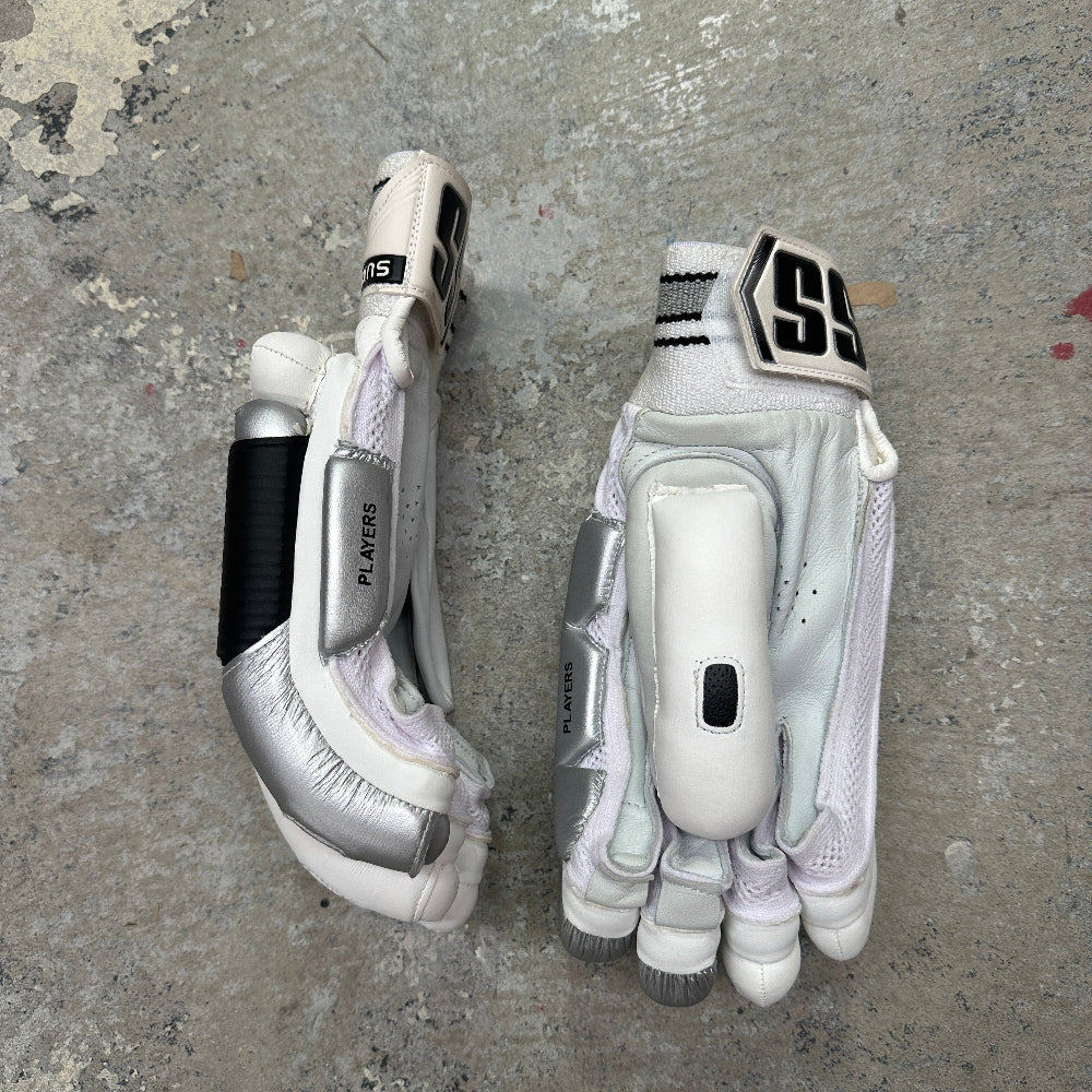 Pair of white and silver SS gloves with brand logo on a gray concrete surface