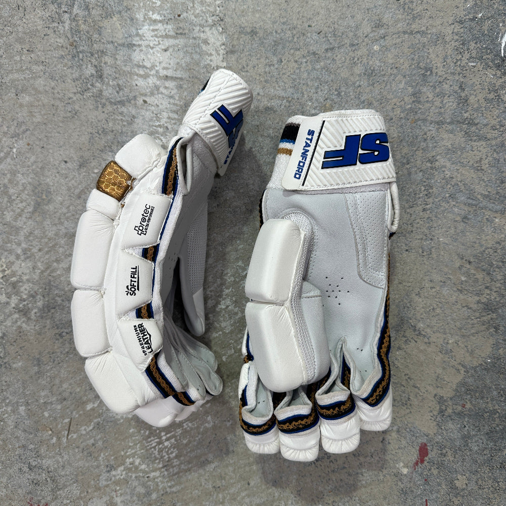 Pair of white cricket gloves with SF brand logos on a gray surface
