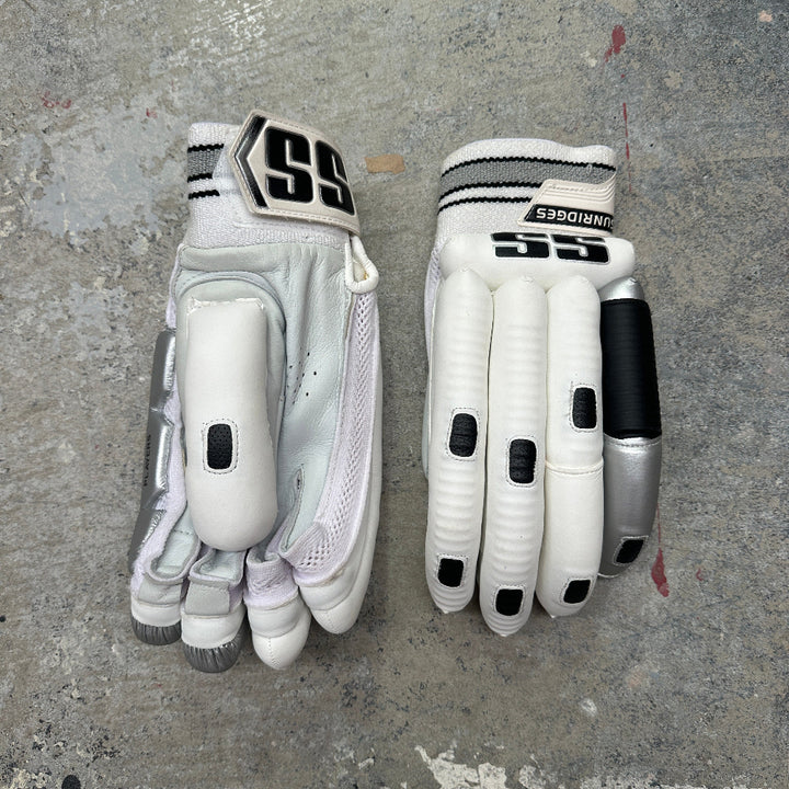 Pair of SS white cricket gloves with black accents on a gray concrete surface